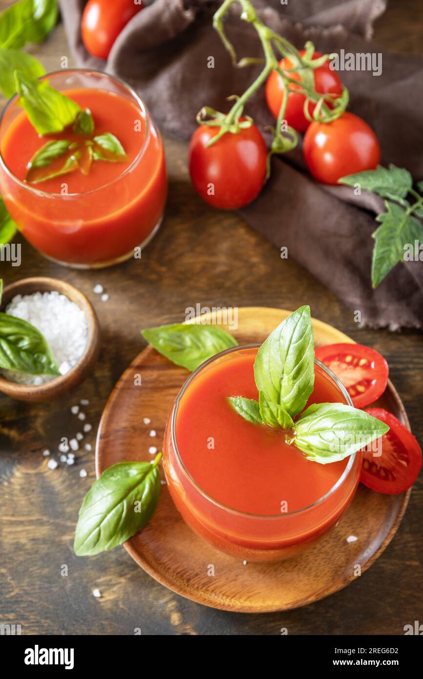 Bicchieri di succo di pomodoro fresco con pomodori, sale su tavola di legno. Bevanda di pomodoro vegetale per una dieta sana. Foto Stock
