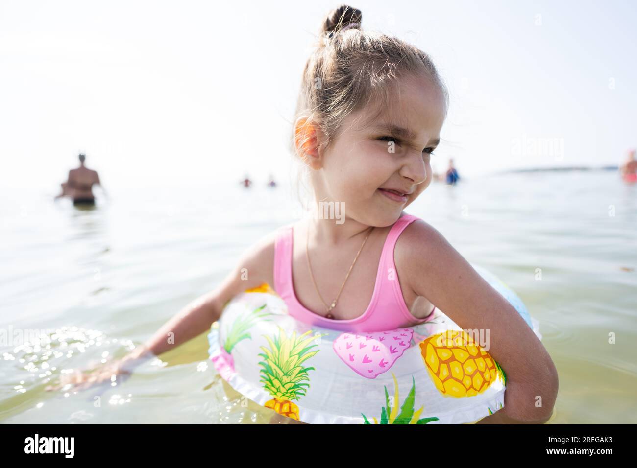 Una bambina carina sta nuotando in mare in un giorno d'estate. Foto Stock