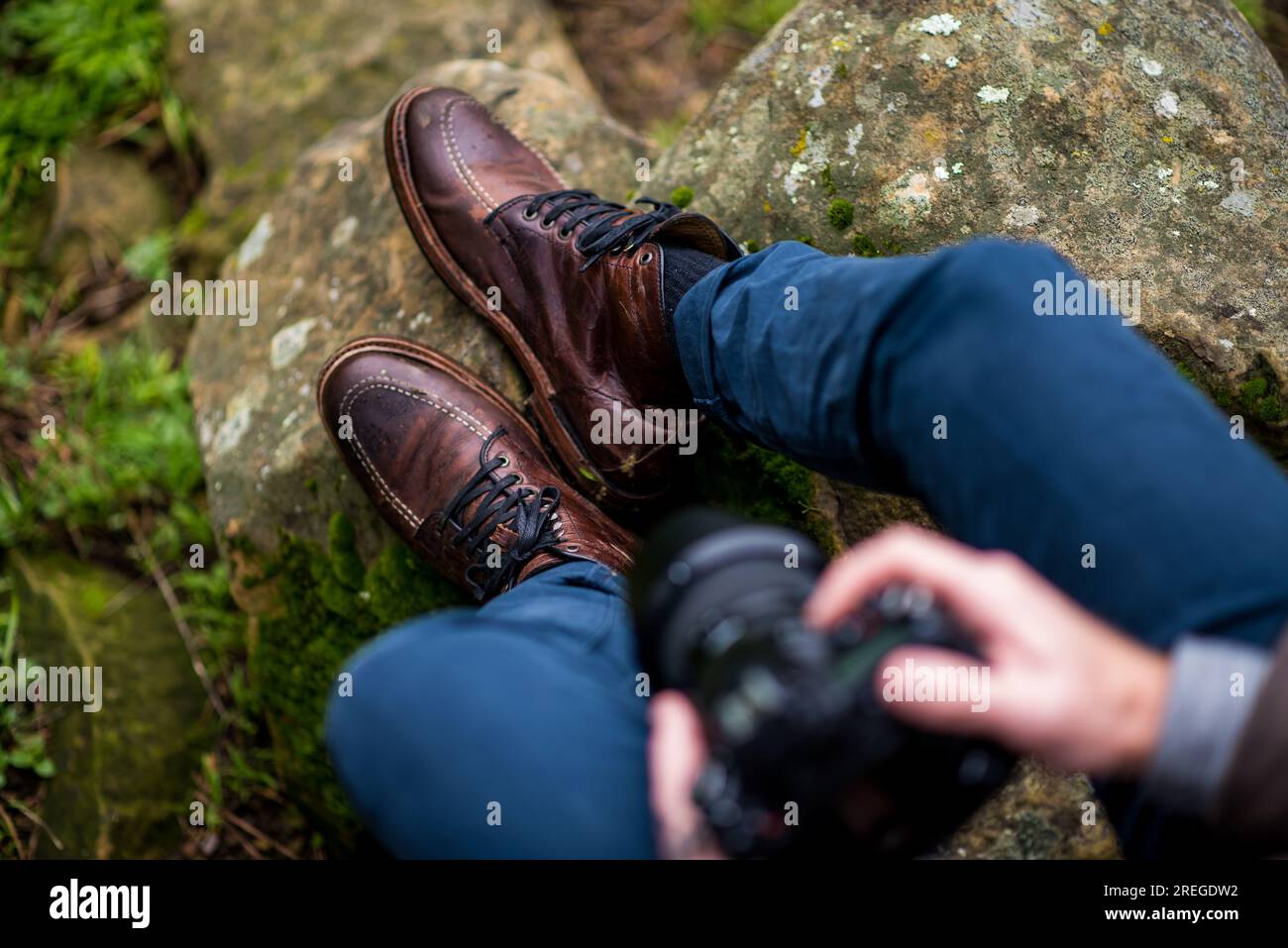 Dettaglio della persona che indossa stivali di pelle seduti sulla pietra Foto Stock
