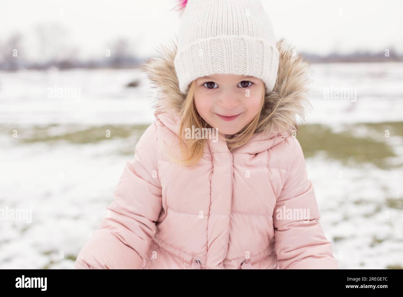 Bambino con occhi espressivi che gioca all'aperto nella neve invernale. Foto Stock