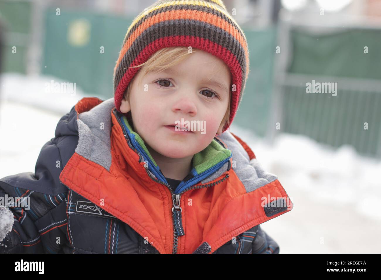 Il bambino gioca all'aperto sulla neve con colori vivaci e divertenti. Foto Stock