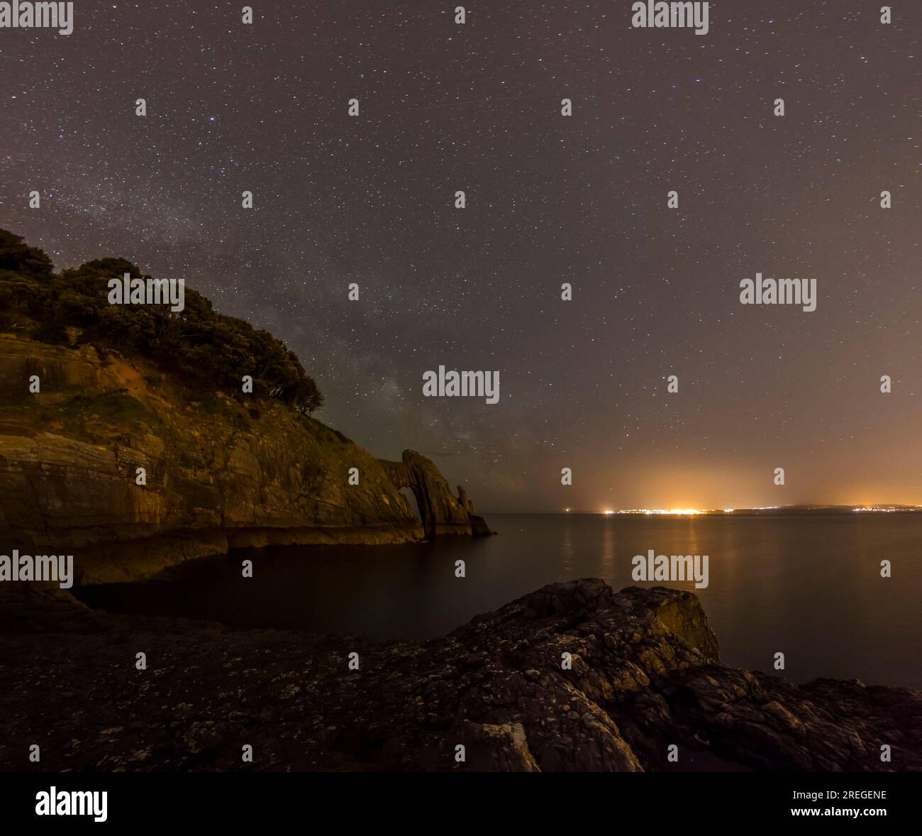 Arco marino naturale e costa di notte con cielo stellato e luci Foto Stock