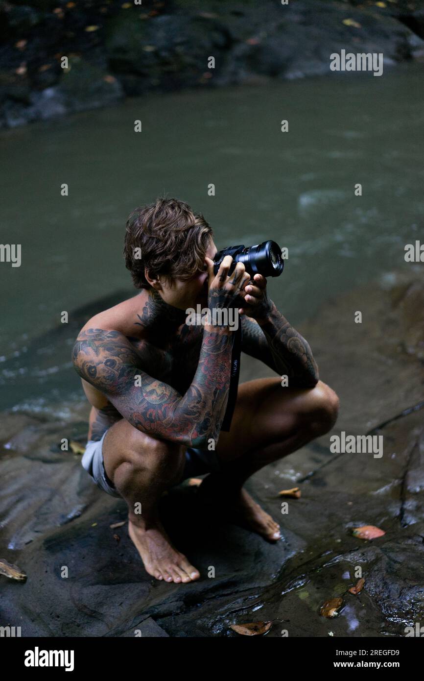 L'uomo tatuato sta scattando foto con una macchina fotografica mentre è in viaggio. Foto Stock