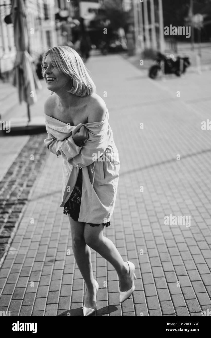 Bella donna bionda con un abito in pizzo su una strada cittadina, sorriso felice. Foto Stock
