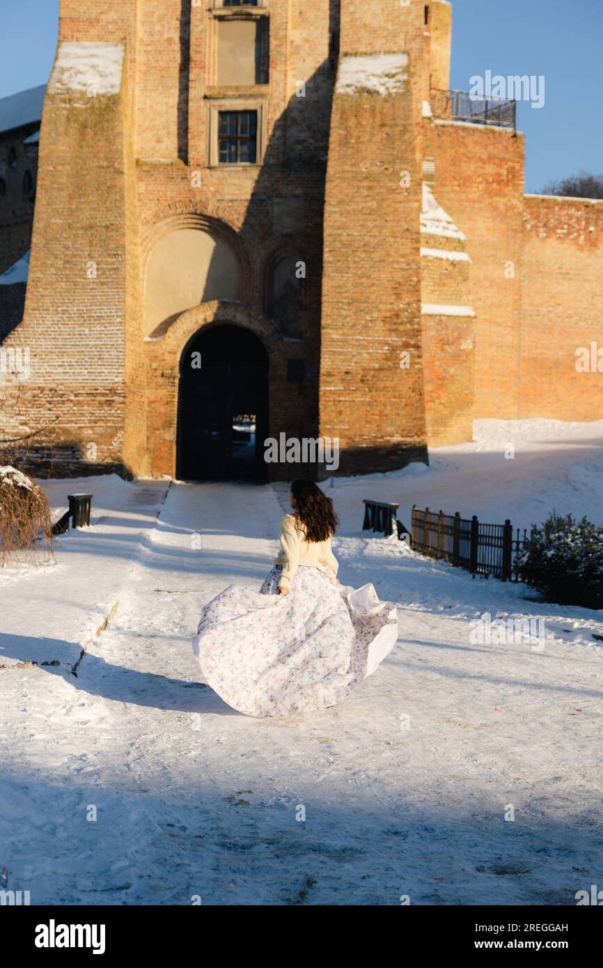 Una ragazza in abito lungo cammina lungo una strada innevata fino al castello Foto Stock