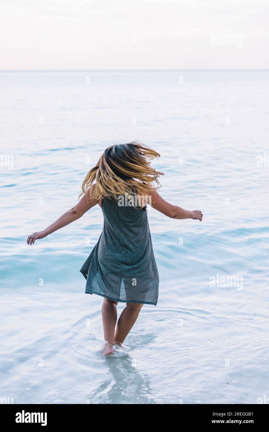 La giovane donna si arrabbia sulla spiaggia tranquilla all'alba. Foto Stock