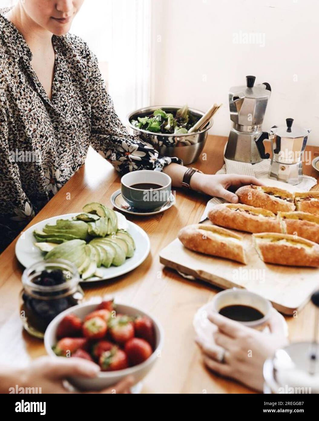 Le giovani donne si riuniscono intorno a un brunch luminoso diffuso a casa Foto Stock