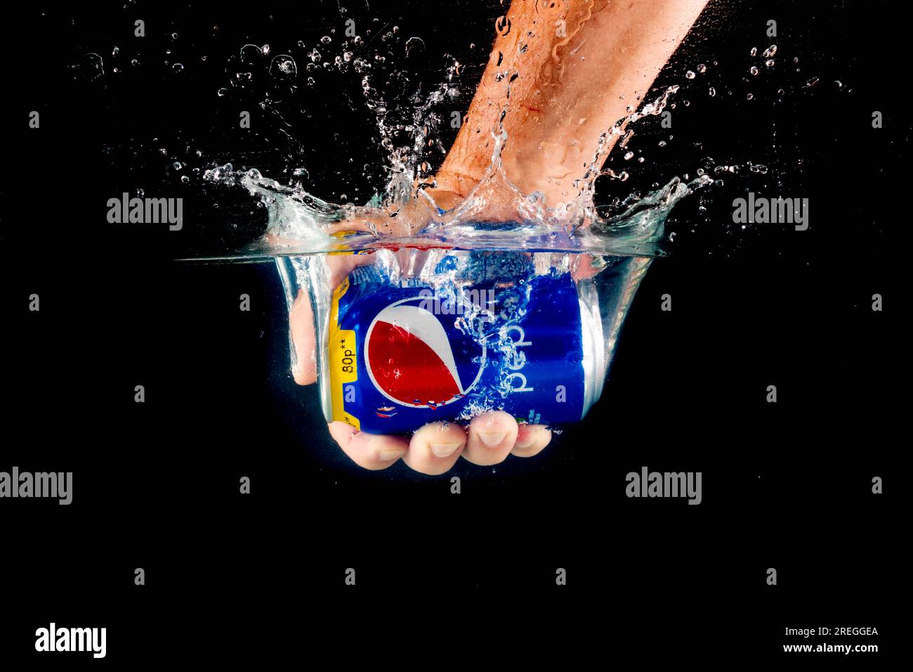 Londra, Regno Unito, 24 luglio 2023: Una lattina di Pepsi tenuta in una mano che spruzza in acqua su uno sfondo nero Foto Stock