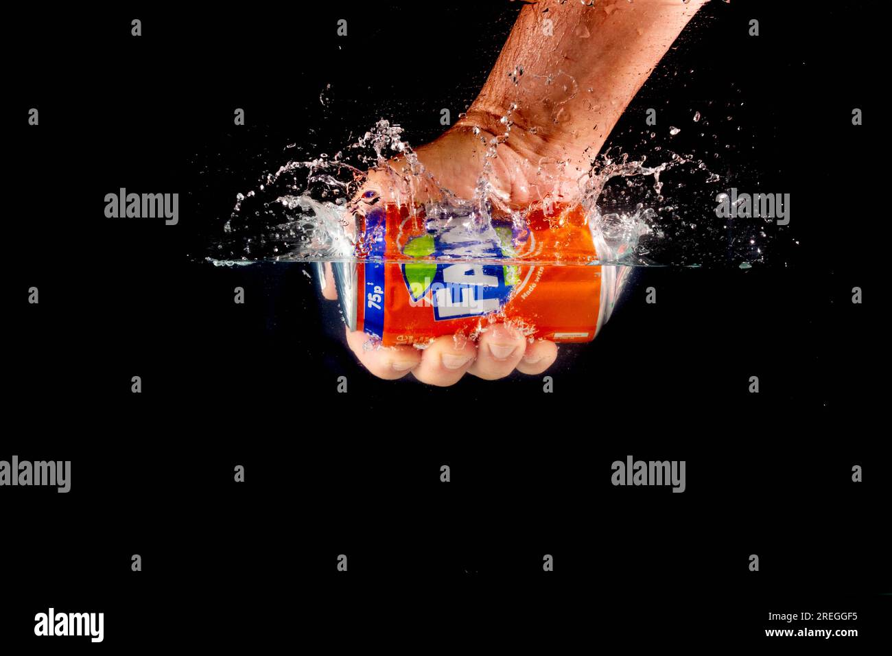 Londra, Regno Unito, 24 luglio 2023: Una lattina di Fanta Orange tenuta da una mano che spruzza in acqua su uno sfondo nero Foto Stock