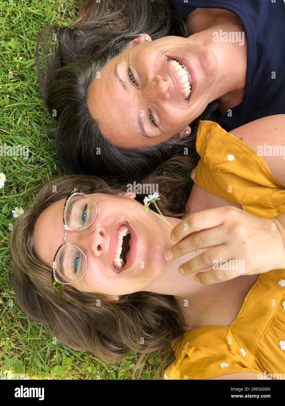 Selfie di madre e figlia adulta sdraiati sull'erba e ridendo Foto Stock