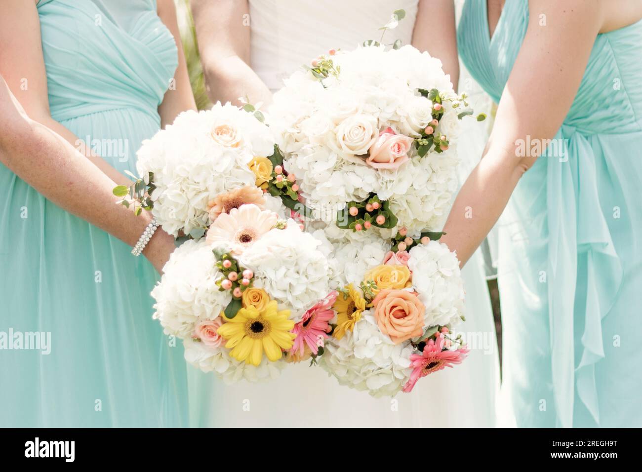 Mazzi da sposa floreali tenuti da una festa nuziale in abiti ottanio Foto Stock
