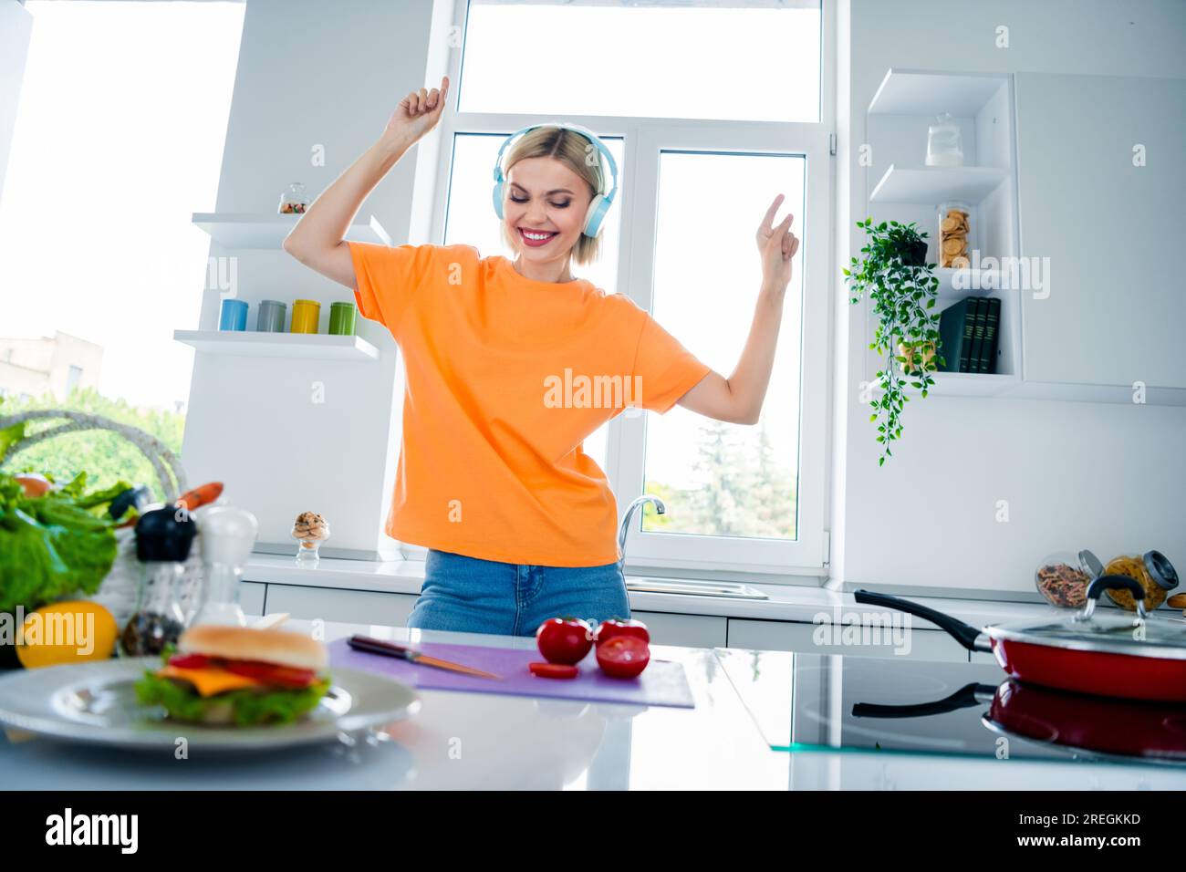 Foto di un allegro piatto da donna che cucina con una danza di pomodoro  fresco con un'energica cuffia melodia in cucina Foto stock - Alamy