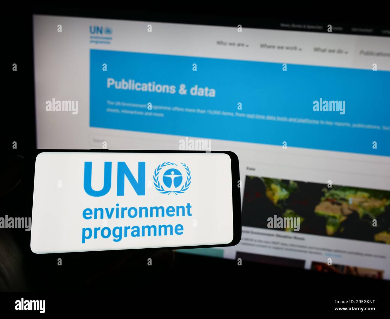 Persona che possiede un telefono cellulare con il logo del programma delle Nazioni Unite per l'ambiente (UNEP) sullo schermo davanti alla pagina Web. Concentrarsi sul display del telefono. Foto Stock