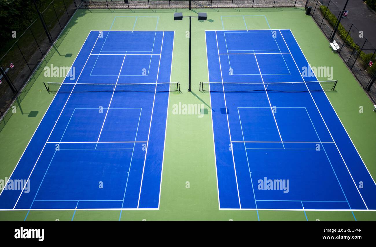 Due campi da Pickleball blu e verde e da tennis visti da un drone sopra con luci e una recinzione nera che circonda i campi Foto Stock