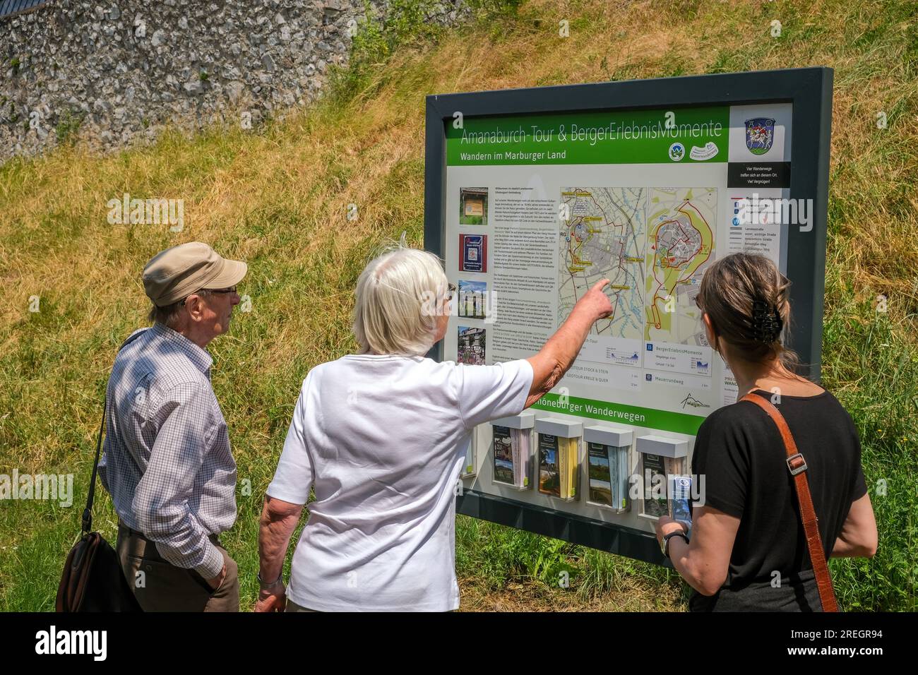 Amöneburg, Assia, Germania - i turisti che camminano lungo il circuito murario, guardano un cartello informativo, una mappa. Amöneburg è una piccola città nel Marburgo-Bi Foto Stock