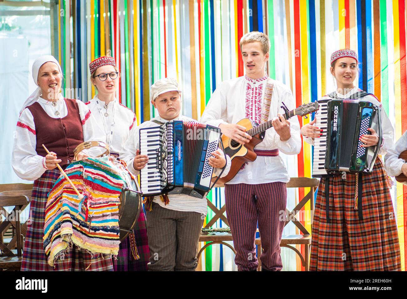 Gruppo di adulti e bambini in abiti tradizionali che suonano e cantano sul palco durante il XXVII Festival della canzone lettone in tutta la nazione e il XVII Festival della danza Foto Stock