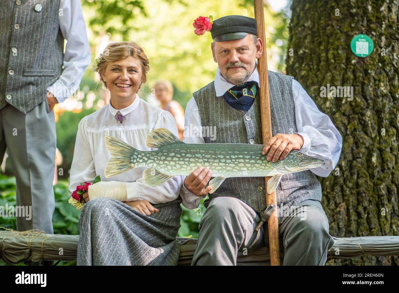 Splendida coppia sorridente in abiti tradizionali e simbolo di pesce durante il XXVII Festival della canzone lettone in tutta la nazione e il XVII Festival della danza Foto Stock