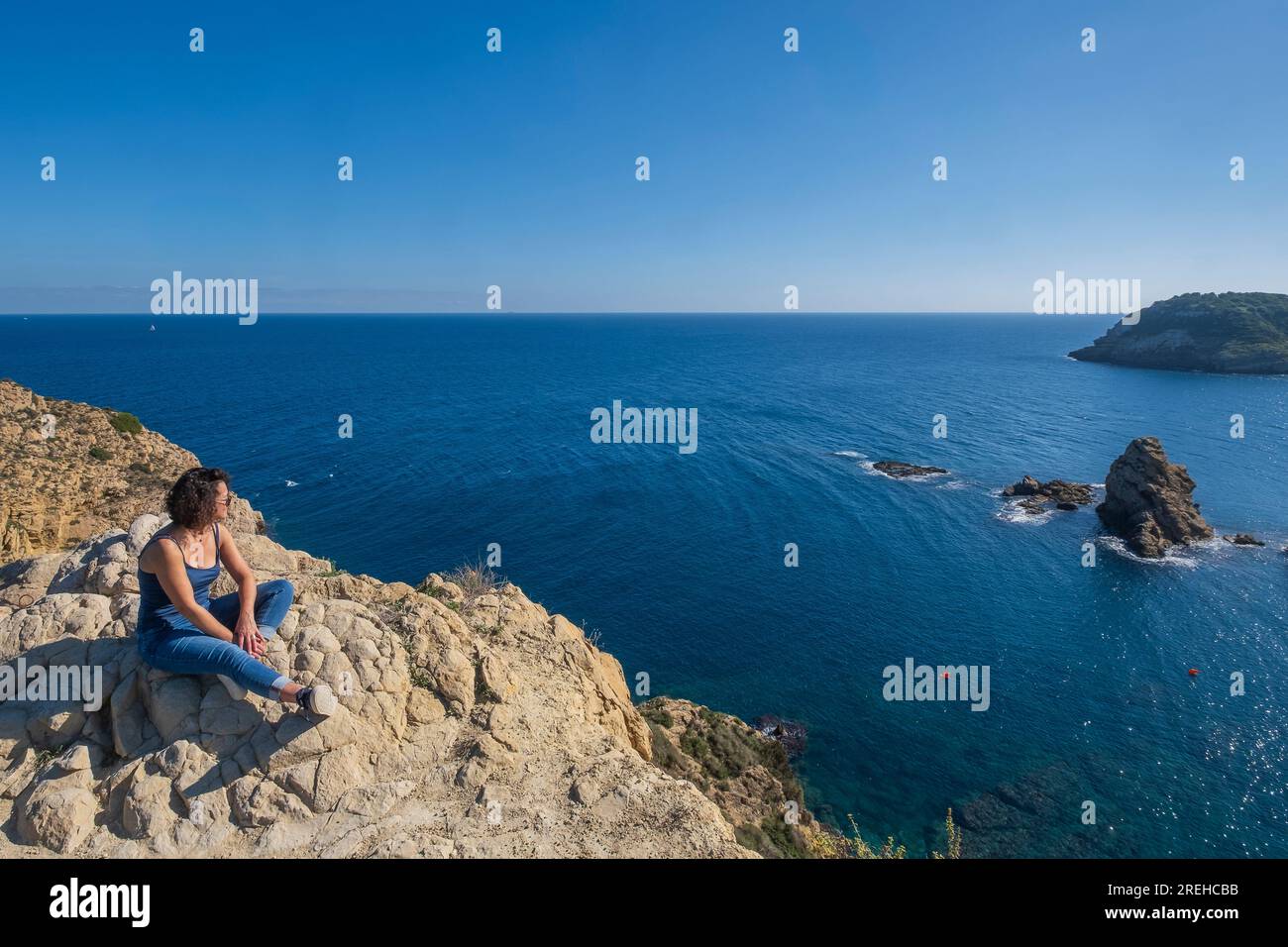 Una donna siede a Javea (Xabia) a Cap prim e guarda al mare. Foto Stock