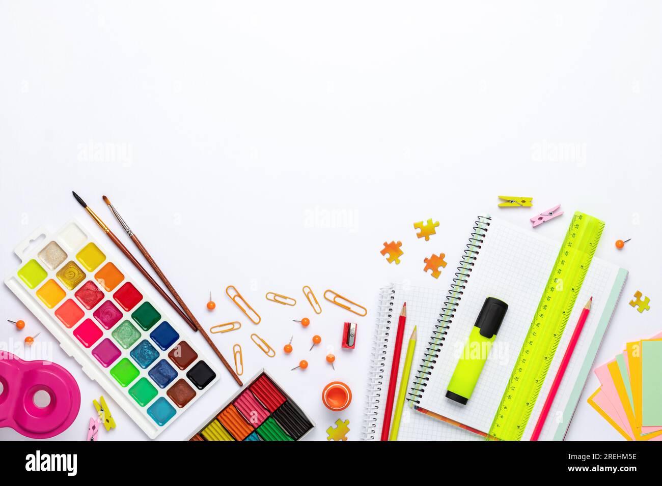 Torna a scuola. Cancelleria diversa su sfondo bianco del tavolo, base piatta. Spazio per il testo. Vista dall'alto. Materiali di consumo colorati, carta bianca, modello didattico. Foto Stock