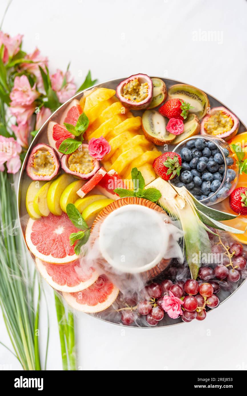 Vassoio assortito di frutta cruda e frutti di bosco sul piatto, sul tavolo bianco Foto Stock