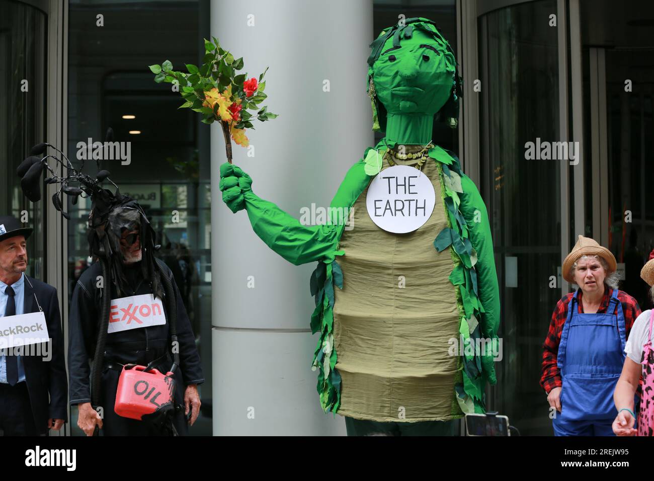 Londra, Regno Unito. 28 luglio 2023. "Exxon & BlackRock, Your Oil Kills" protesta fuori dalla sede centrale di BlackRock organizzata dagli attivisti del clima Extinction Rebellion Lewes con il teatro di strada Crude Oil Mechanicals. La Crude Oil Mechanicals è un gruppo di persone che vivono a Lewes, Brighton e Eastbourne, che si riuniscono per eseguire spettacoli di strada a sostegno delle proteste per la giustizia climatica. "Unfinished Story" è un'opera completamente nuova, con la partecipazione di Terra, Sole, acqua, un'enorme compagnia petrolifera, un enorme fondo di investimento e alcune persone comuni. Crediti: Waldemar Sikora/Alamy Live News Foto Stock