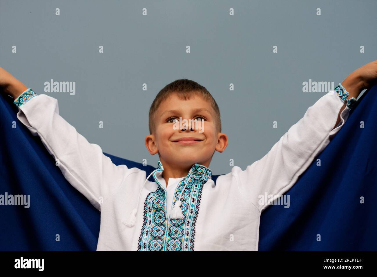 Felice ragazzo ucraino in camicia ricamata - vyshyvanka con bandiera blu-gialla dell'Ucraina, contro il cielo. Giorno dell'indipendenza dell'Ucraina. Giorno della Costituzione. Da Foto Stock