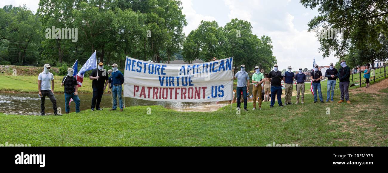 Prattville, Alabama, USA - 24 giugno 2023: Membri del Patriot Front, un gruppo di odio nazionalista bianco, neo-fascista, si coprono il volto tenendo in mano una banne Foto Stock