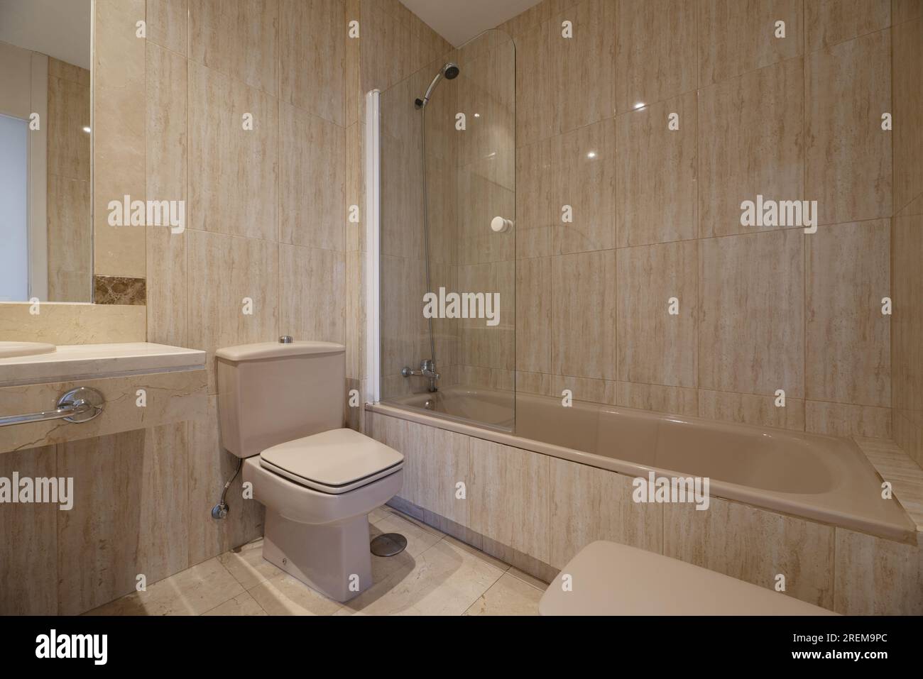 Bagno completo di una casa con uno specchio con cornice in marmo, un ripiano realizzato con lo stesso materiale con un lavandino in porcellana beige, un asciugamano cromato rai Foto Stock