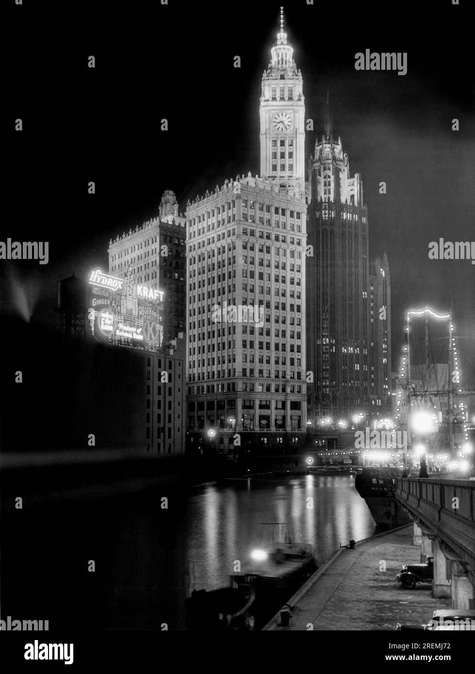 Chicago, Illinois: c. 1936. Il Wrigley Building a sinistra con la Tribune Tower a destra, vista di notte attraverso il fiume nello skyline di Chicago. Foto Stock