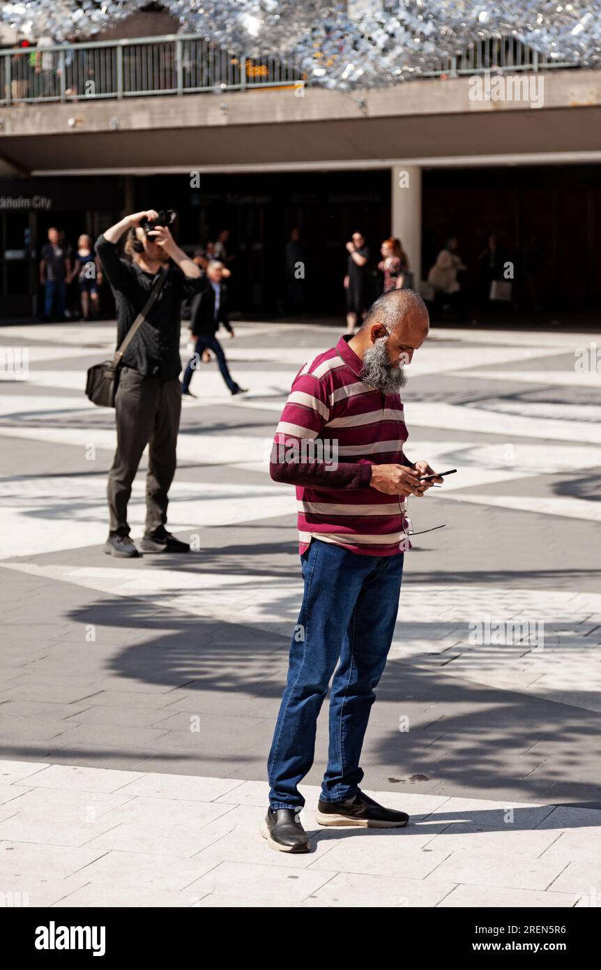 Stoccolma, Svezia - 23 maggio 2023: Uomo con la barba lunga che guarda il suo cellulare Foto Stock