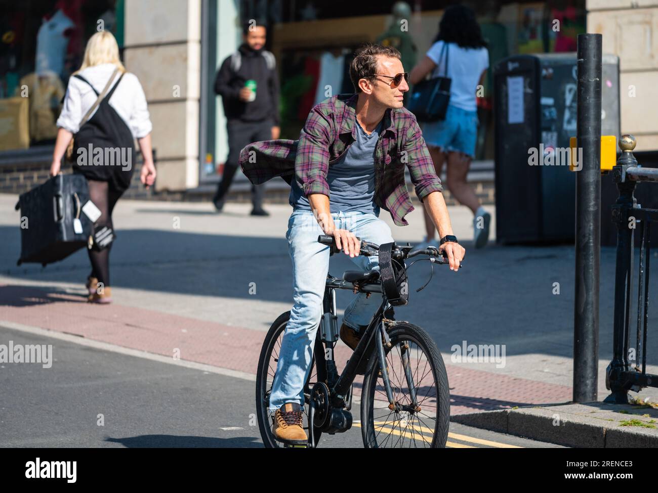 Giovane ciclista maschile, giovane in bicicletta su strada in una città frenetica d'estate, senza indossare il casco, in Inghilterra, Regno Unito. Stile di vita sano. Foto Stock