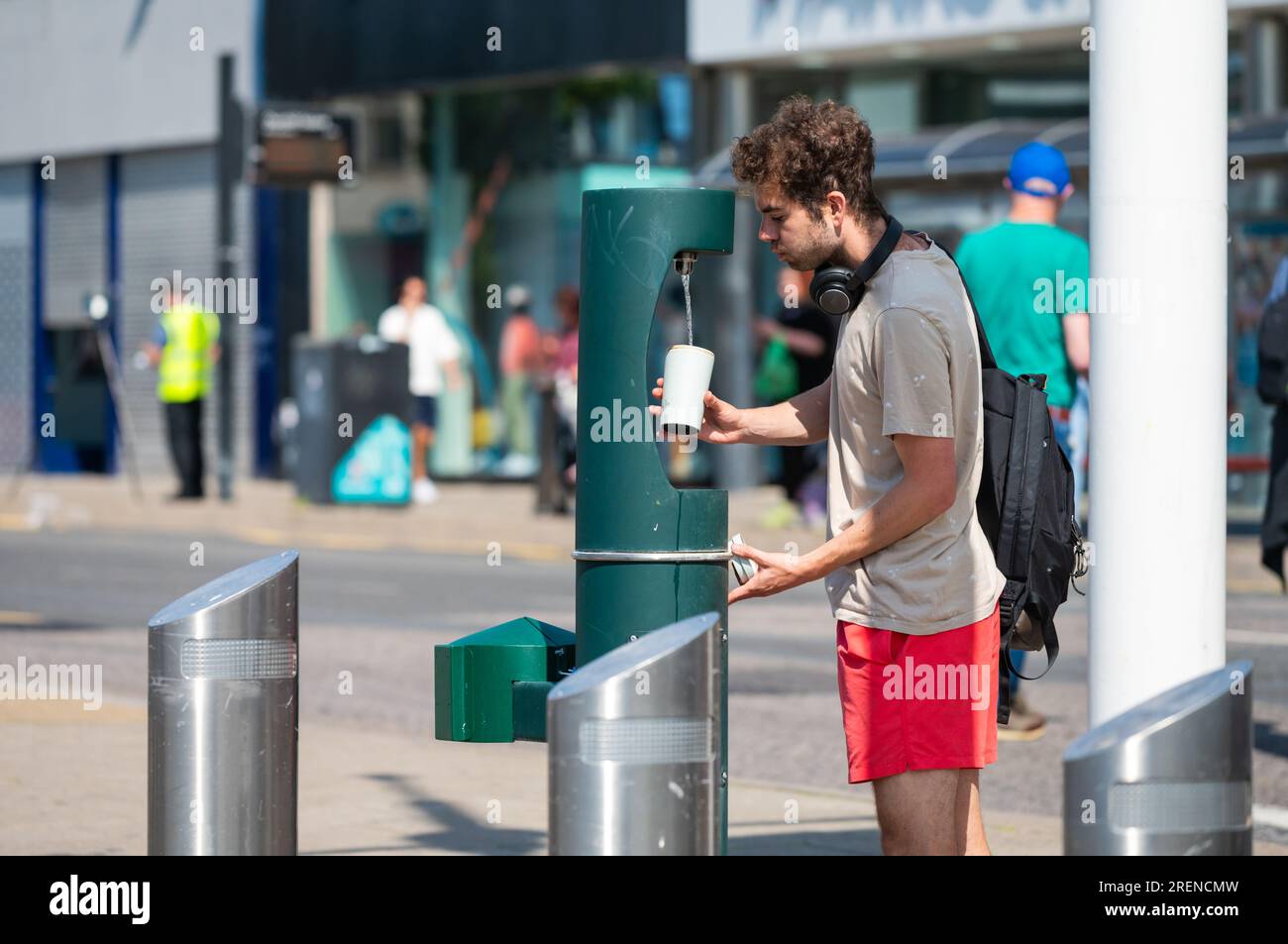 Giovane che riempie una tazza di acqua da un erogatore di acqua pubblica o da una fontana di acqua potabile Estate a Brighton, Brighton & Hove, Inghilterra, Regno Unito. Foto Stock