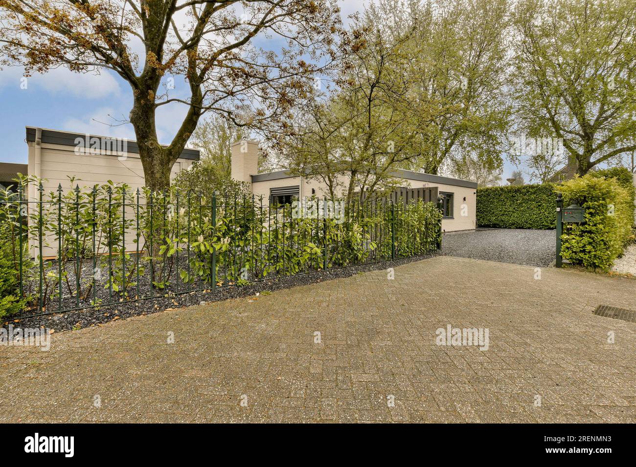 una casa con alberi nel cortile anteriore e cespugli su entrambi i lati del vialetto, come si vede dalla strada Foto Stock