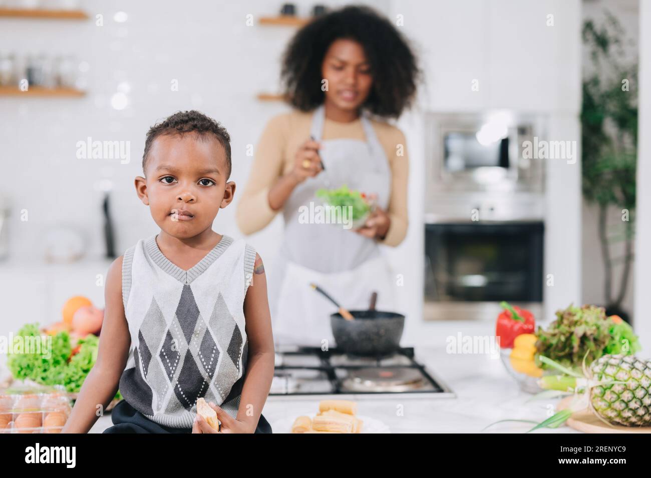 felice madre nera africana con il suo ragazzo adorabile cucina carina insieme durante le vacanze a casa Foto Stock