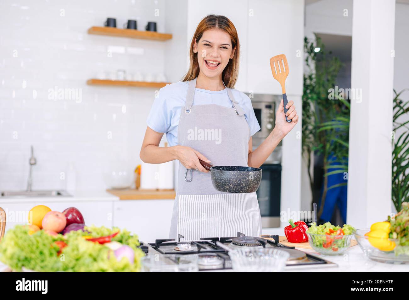ritratto donna felice che cucina cibo sano insalata di verdure in cucina con tablet online Foto Stock