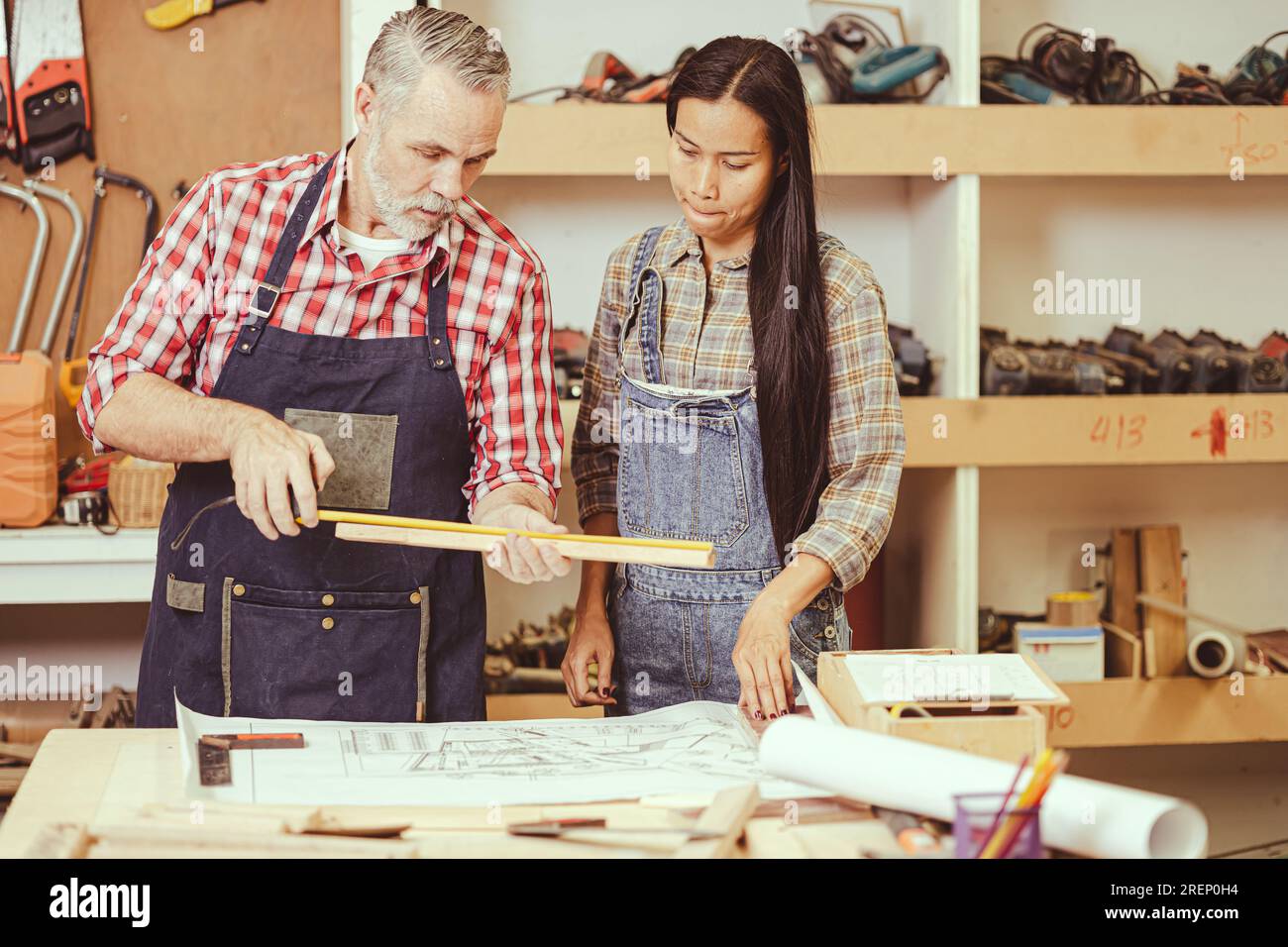 Professionista senior caucasico maschio fai da te lavorazione del legno che realizza mobili per la casa fissi in officina che aiuta la moglie. Foto Stock