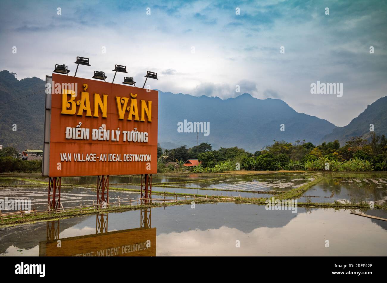 Un grande cartello rosso con luci di lettura si riflette nelle risaie in quanto pubblicizza il villaggio Van della minoranza etnica thailandese bianca a mai Chau, in Vietnam, come un Foto Stock