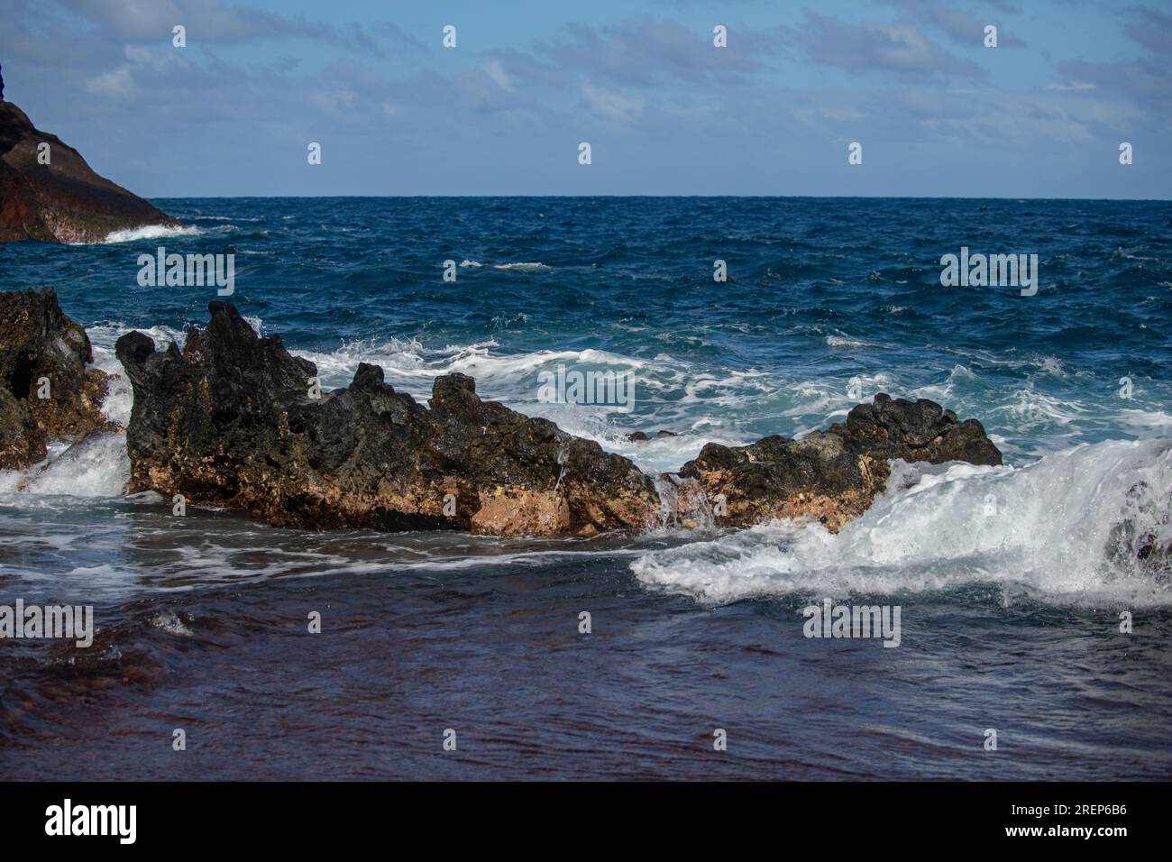 Sfondo mare. L'onda dell'oceano si schiantano sulla costa rocciosa con spruzzi e schiuma prima della tempesta. Foto Stock