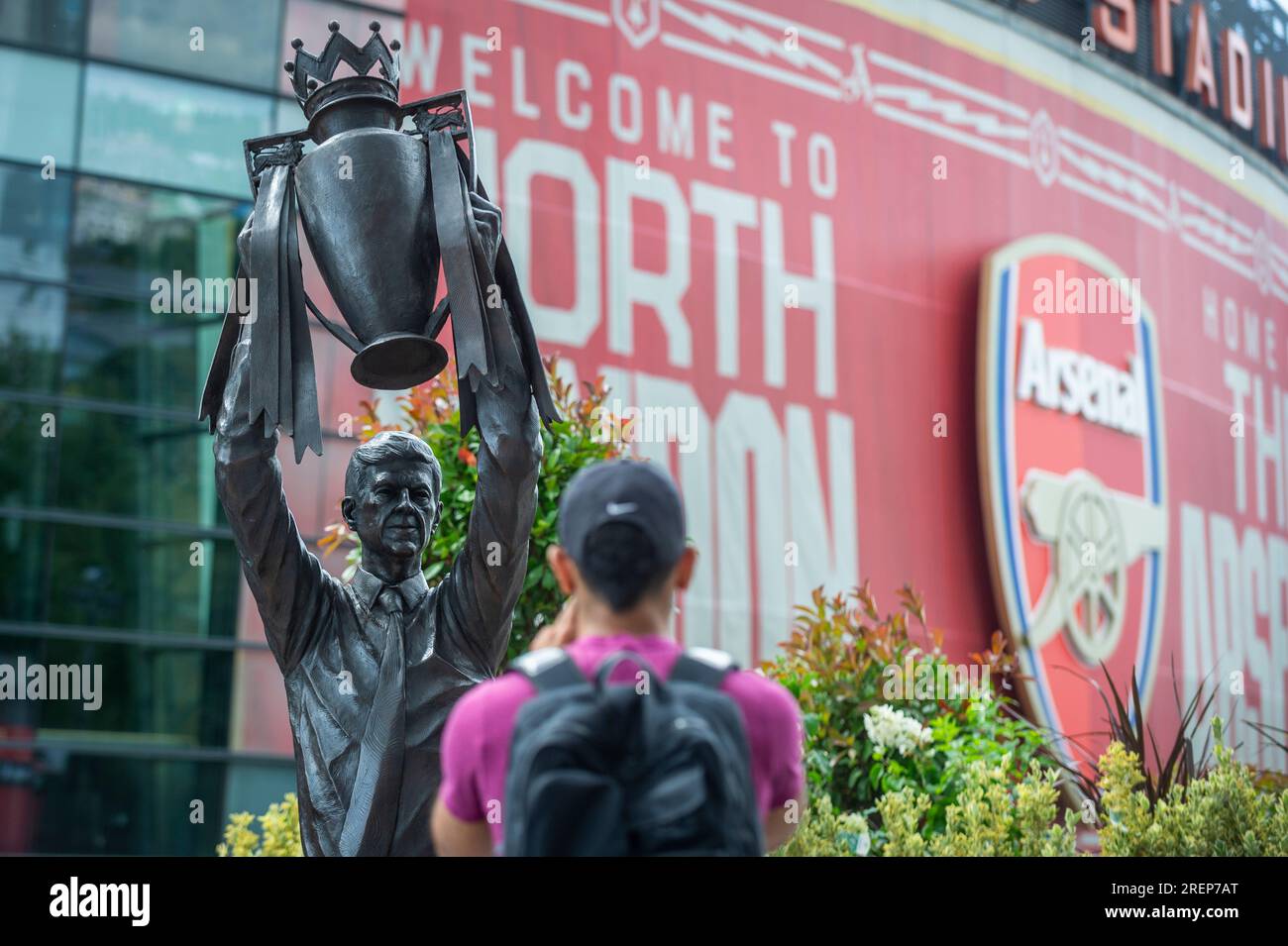 Londra, Regno Unito. 29 luglio 2023. Un tifoso vede la statua del manager dell'Arsenal Arsène Wenger che detiene il trofeo della Premier League che è stato installato all'esterno dell'Emirates Stadium il giorno precedente. Il leggendario allenatore guidò l'Arsenal FC a tre titoli di Premier League, tra cui la famosa stagione degli Invincibles nel 2003/04, dove la sua squadra rimase imbattuta, e sette fa Cup. Creata dallo scultore Jim Guy, la statua di bronzo è alta 3,5 m e pesa quasi mezza tonnellata. Crediti: Stephen Chung / Alamy Live News Foto Stock