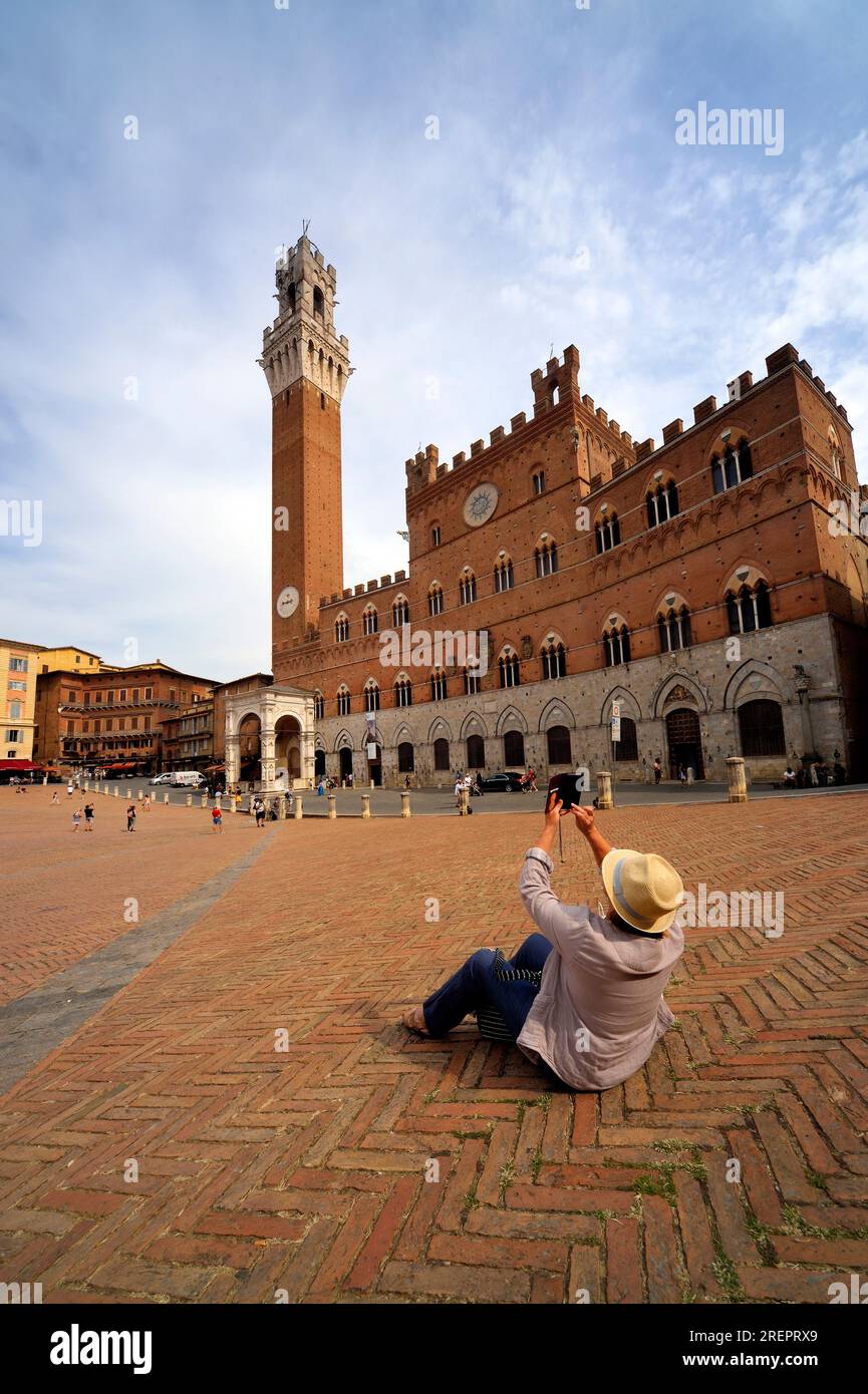 Siena, Italia - 10 settembre 2021: Un turista gode di Piazza del campo, Palazzo Publico e Torre del Mangia Siena, Italia. Foto Stock