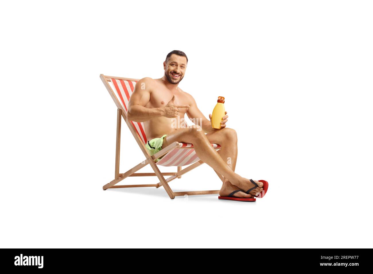 Un giovane che tiene in mano una bottiglia di crema solare seduto su una sdraio isolata su sfondo bianco Foto Stock