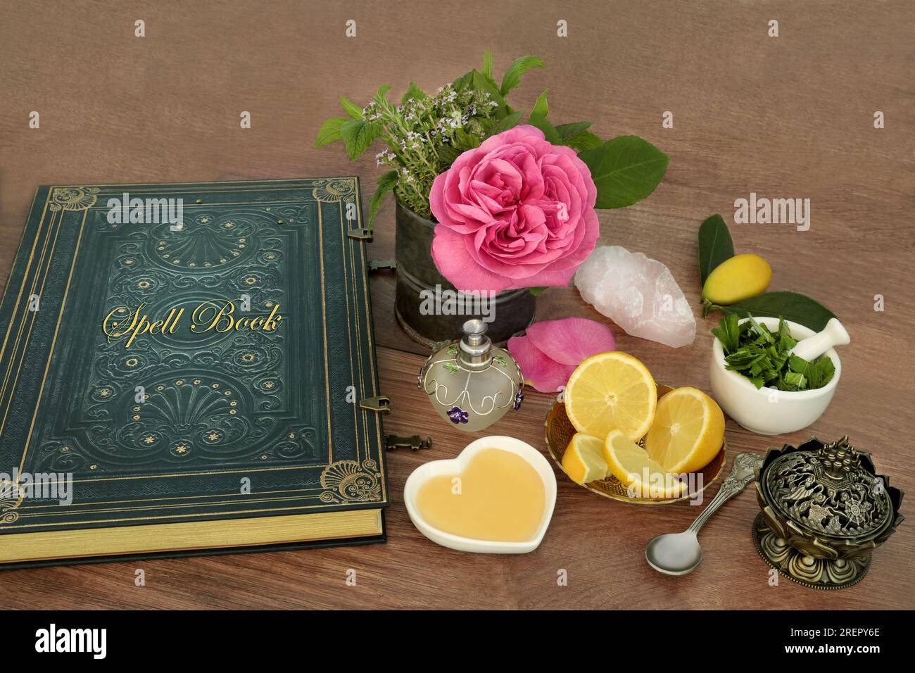 Preparazione di pozioni d'amore per incantesimi magici con ingredienti di fiore di rosa, cristallo di quarzo, timo, menta, limone e miele con un vecchio libro di incantesimi. Foto Stock