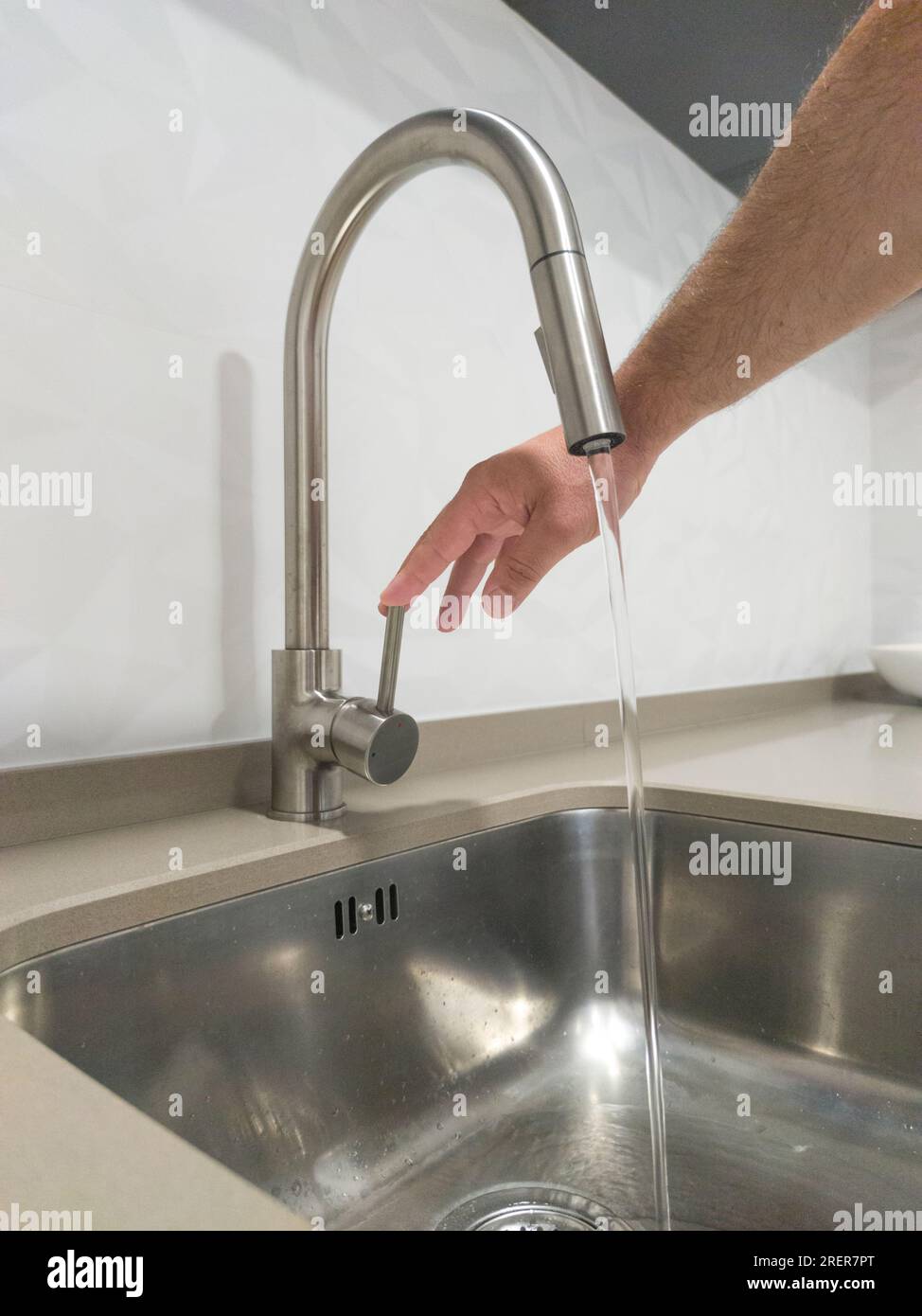 Mano maschio che apre il rubinetto del lavandino della cucina. Messa a fuoco selettiva Foto Stock
