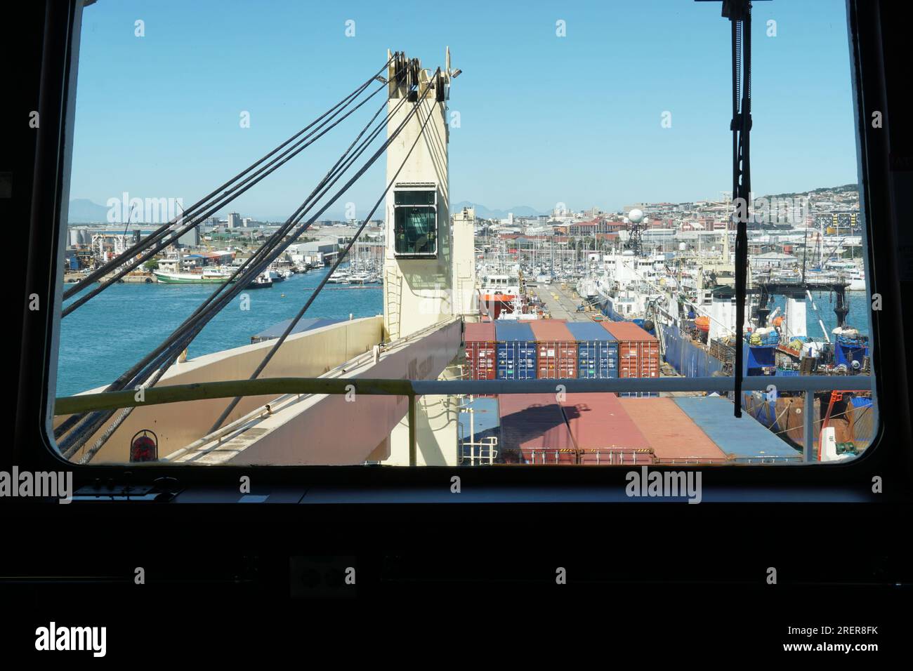 Vista dal ponte di navigazione sulla cabina della gru della nave con filo di acciaio lubrificato della nave container caricata. Foto Stock
