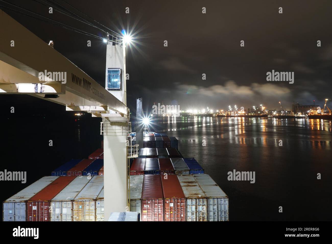 Nave container caricata con gru ancorate vicino al porto di Paranagua durante la notte con cielo coperto. Foto Stock