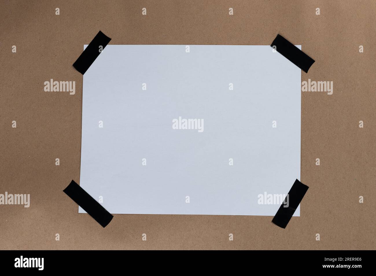 Carta bianca attaccata con nastro adesivo sul bordo su sfondo marrone riciclato Foto Stock