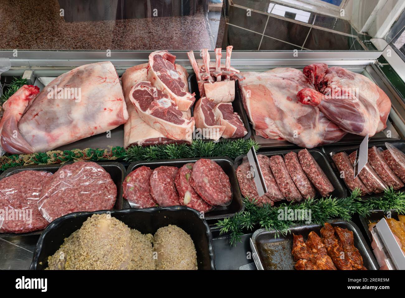 La macelleria dispone di un'esposizione refrigerata con una varietà di carni fresche crude tra cui scegliere. Ledbury DT Waller e Sons Foto Stock