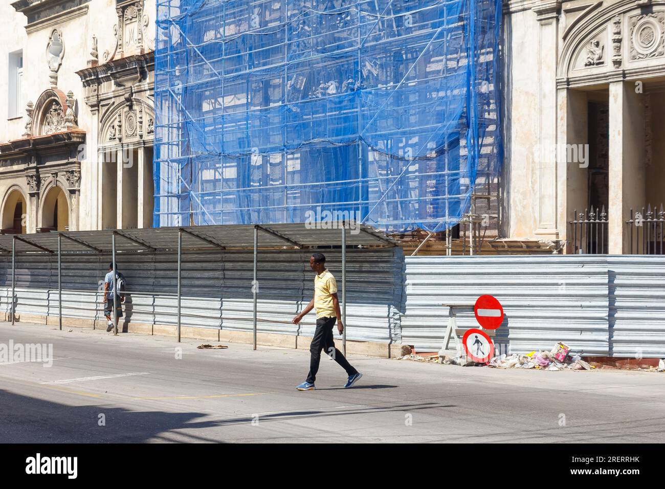 L'Avana, Cuba, un uomo afro-caraibico di etnia cubana attraversano la strada da un edificio in ricostruzione nella capitale Foto Stock