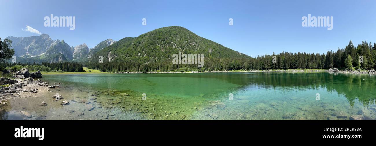Vista panoramica delle acque turchesi del Lago Die Fusine superiore nelle Alpi Giulie dell'Italia nord-orientale con la parete rocciosa del Monte Mangart Foto Stock