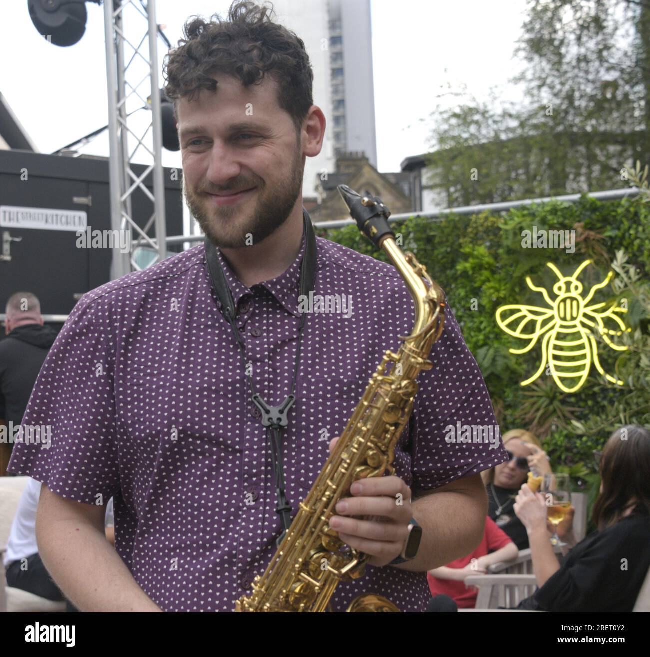Manchester, Regno Unito, 29 luglio 2023. Un musicista intrattiene i clienti, suonando il suo sassofono al Capri Beach Bar, Exchange Square. Manchester Day - in vacanza!, gratuito, divertente, adatto alle famiglie, eventi per le strade del centro di Manchester, Regno Unito. Sostenuto dal Manchester City Council, Manchester Airport Group, Biffa, The Co-op, Manchester Evening News, Cammina sul Plank, il Regno dei dolci, il British Firefighter Challenge e il Capri Beach Club. Credito: Terry Waller/Alamy Live News Foto Stock